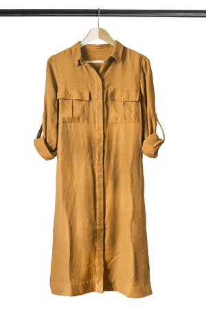 Yellow silk dress on wooden clothes rack isolated over whiteの写真素材