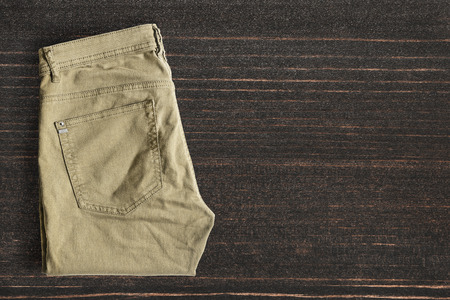 Folded khaki pants on dark wooden backgroundの写真素材