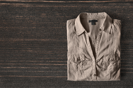 Folded khaki shirt on dark wooden backgroundの写真素材