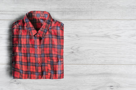 Red tartan shirt folded on white wooden backgroundの写真素材