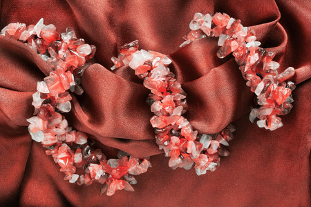 Strings of carnelian beads on red crumpled satin as a backgroundの写真素材