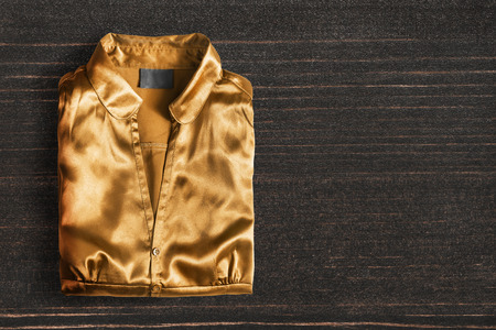 Golden satin blouse folded on dark wooden backgroundの写真素材