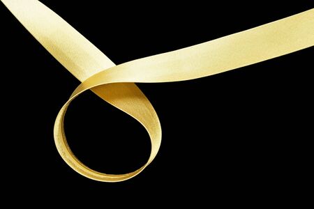 Golden silk ribbon on black backgroundの写真素材