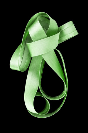 Green satin ribbon knotted on black backgroundの写真素材