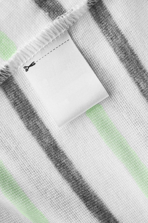 Blank clothes label on striped cloth as a backgroundの写真素材
