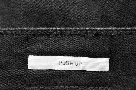 White clothes label lettered push up on black denim