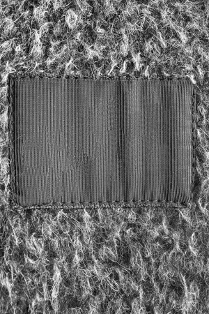 Black blank clothes label on gray wool as a backgroundの写真素材