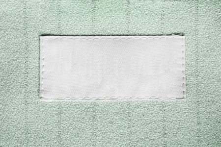 Blank white clothes label on green cloth as a backgroundの写真素材