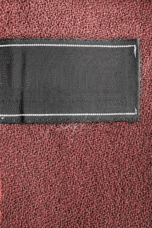 Blank black clothes label on brown cloth as a backgroundの写真素材