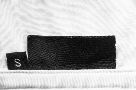 Black blank clothes label on white cloth as a backgroundの写真素材