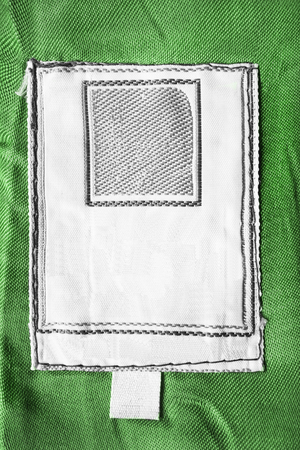 Blank white clothes label on green cloth as a backgroundの写真素材