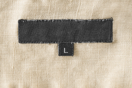 Black clothes label on beige linen as a backgroundの写真素材