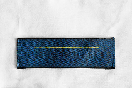 Blank blue clothes label on white cotton as a backgroundの写真素材