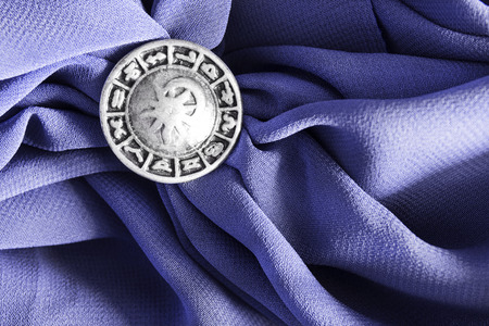 Silver zodiac brooch on purple crumpled silk as a backgroundの写真素材