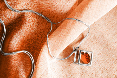 Silver necklace on orange chiffon as a backgroundの写真素材