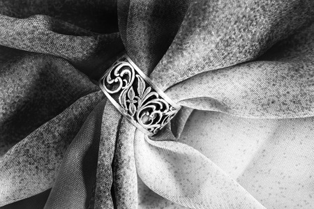 Silver carved ring on black and white draped clothの写真素材