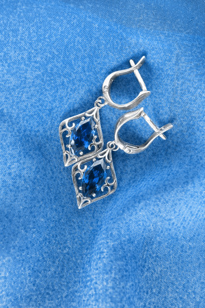 Sapphire earrings on blue cloth as a backgroundの写真素材