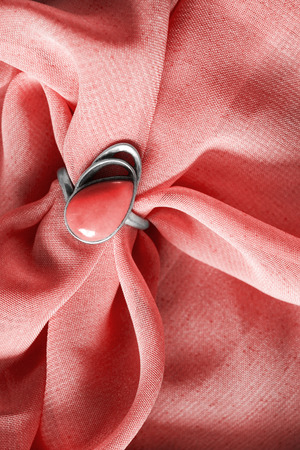 Silver coral ring on pink draped cloth as a backgroundの写真素材