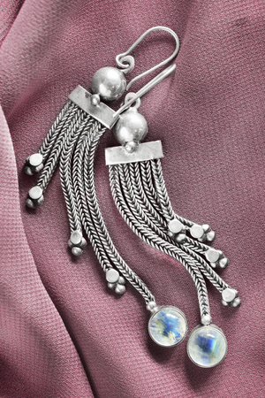 Silver chains earrings on crumpled pink silk as a backgroundの写真素材