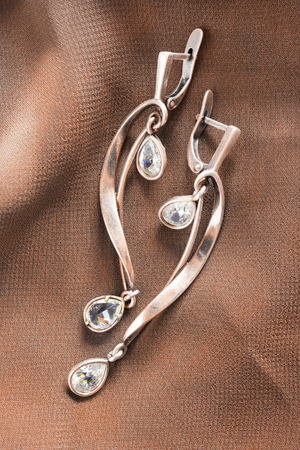 Golden earrings with diamonds on brown silk as a backgroundの写真素材