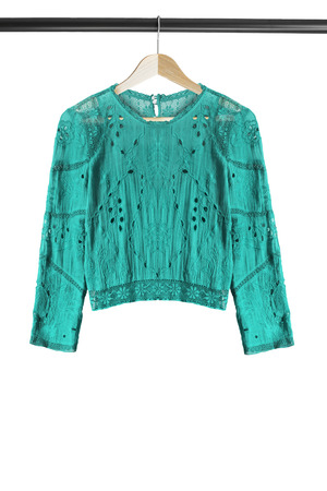 Ethnic cyan blouse on wooden clothes rack isolated over whiteの写真素材