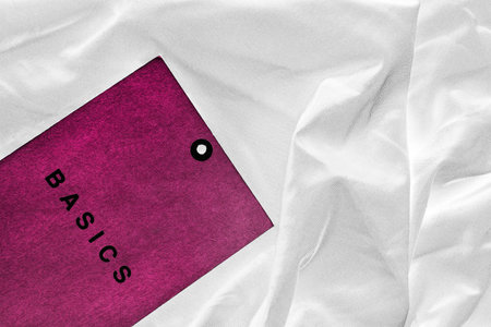 Pink label lettered basics on white crumpled silk as a background