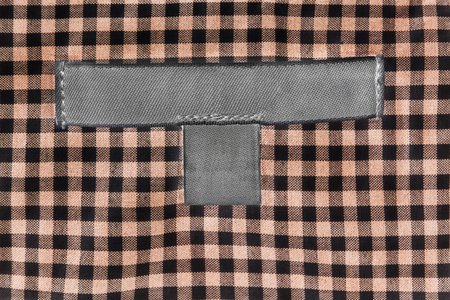 Blank gray clothes label on plaid cloth as a backgroundの写真素材