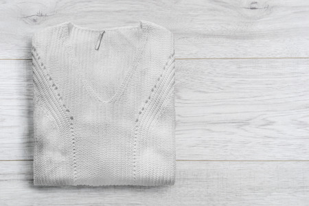 White knitted pullover folded on white wooden backgroundの写真素材