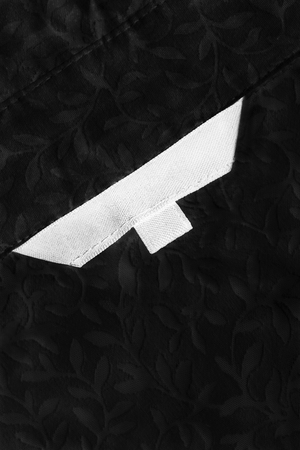 Blank white clothes label on black lacy cloth as a backgroundの写真素材