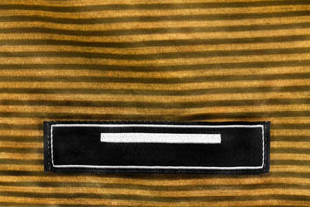 Blank clothes label on striped yellow cloth as a background
