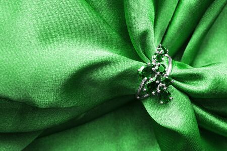 Emerald ring on green crumpled satin as a backgroundの写真素材