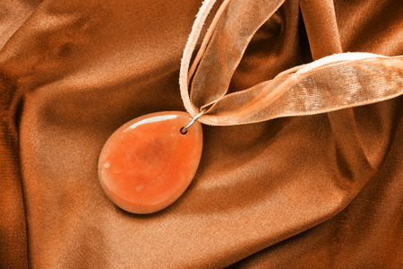 Amber pendant on orange crumpled silk as a backgroundの写真素材