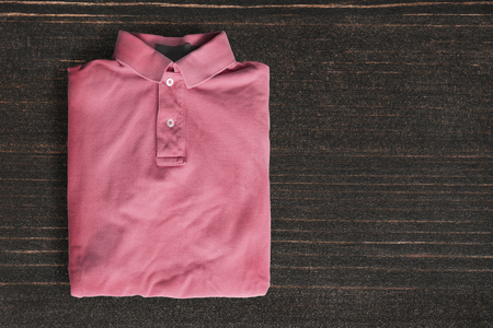 Folded pink polo shirt on dark wooden backgroundの写真素材