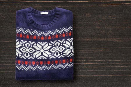Knitted wool sweater folded on dark wooden backgroundの写真素材