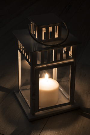 Burning candle lamp in the dark closeup on wooden floorの写真素材