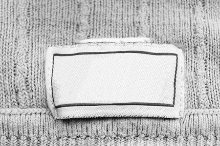 Blank white clothes label on white knitted background