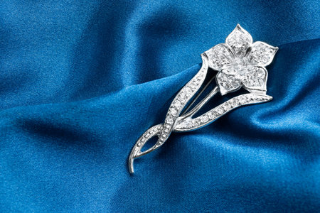 Diamonds flower shaped brooch on blue satin backgroundの写真素材