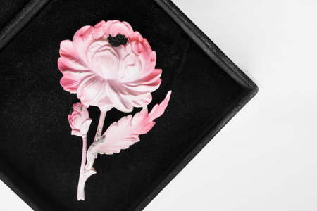 Pink metal flower brooch in black jewel box closeupの写真素材