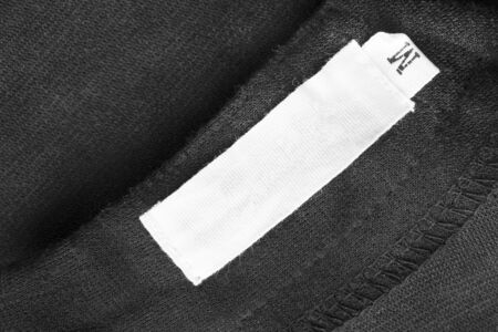 Blank white clothes label on black cloth as a backgroundの写真素材