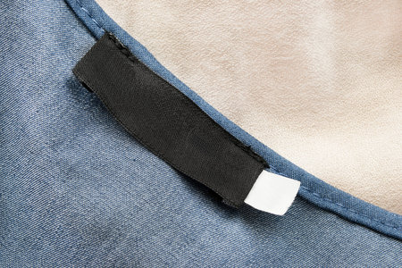 Blank black clothes label on blue cotton as a backgroundの写真素材