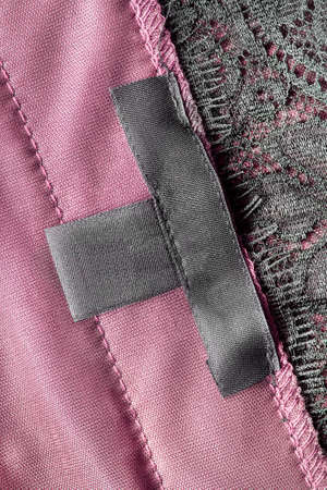 Black black clothes label on pink satin as a backgroundの写真素材