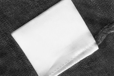 White blank clothes label on black knitted background closeup