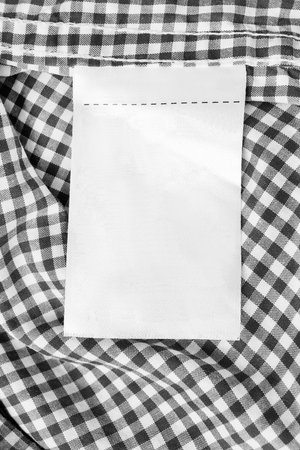 Blank clothes label on black and white plaid crumpled cloth