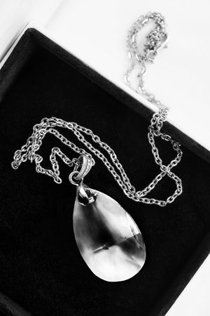 Large crystal pendant on silver chain in black jewel box closeupの写真素材