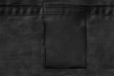 Black blank clothes label on black cloth as a backgroundの写真素材