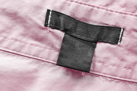 Blank black clothes label on pink cotton as a backgroundの写真素材