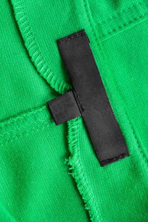 Blank black clothes label on green cotton as a background