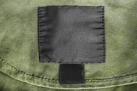Blank black clothes label on khaki denim as a backgroundの写真素材
