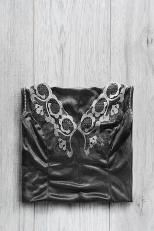 Black lacy satin dress folded on wooden backgroundの写真素材