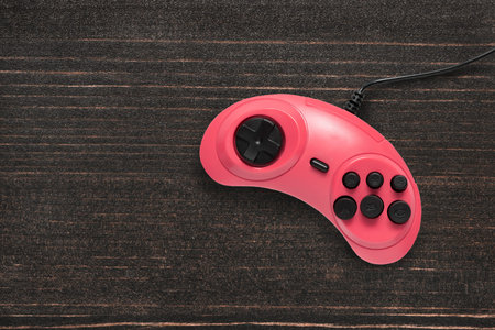Single pink video game controller on dark wooden background